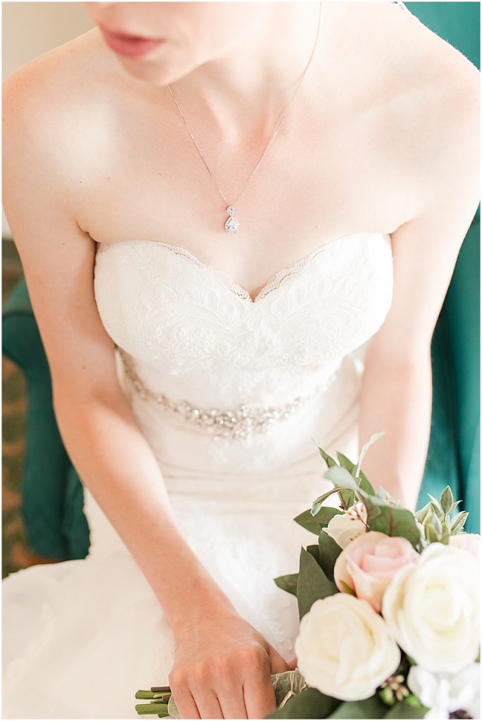 Focused image on bride’s tear drop charm necklace and The sweetheart neckline Of her dress