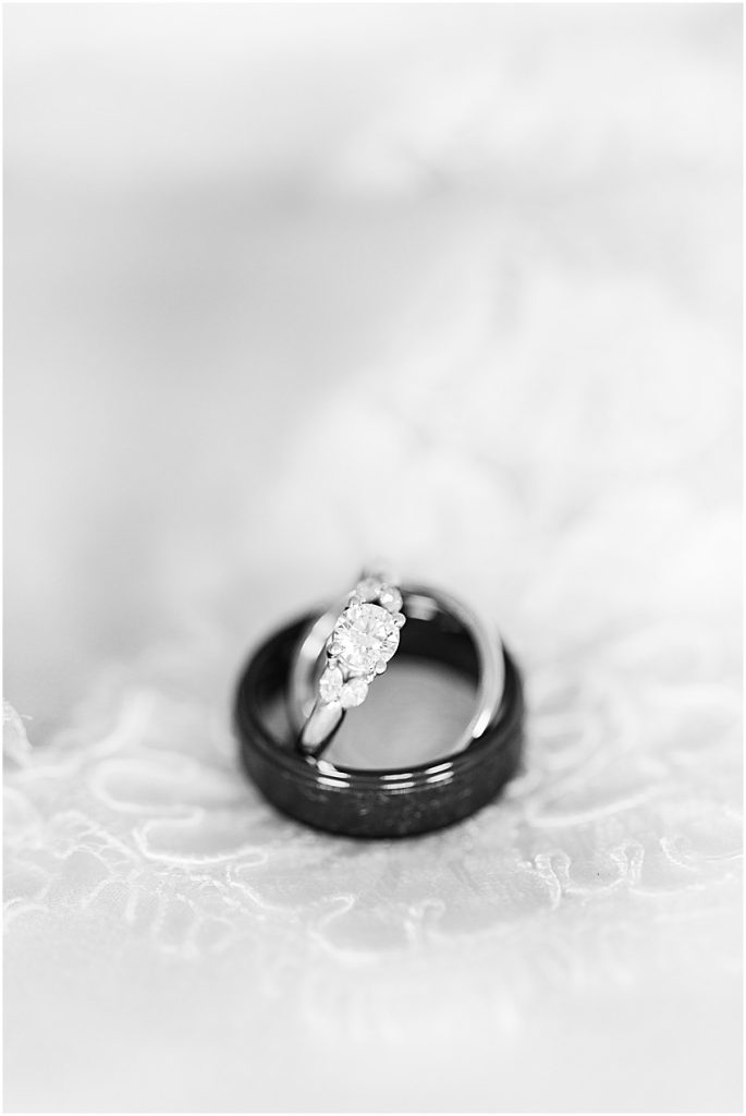 Black and white image of round cut diamond engagement ring balanced inside a men’s dark grey wedding band. 